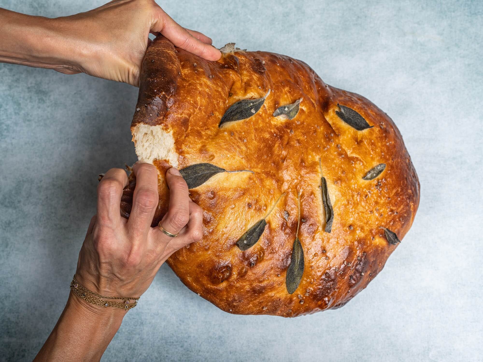 תמונה של ידיים בוצעות לחם עגול ושטוח